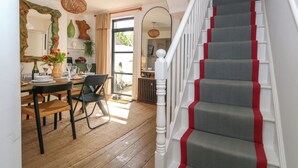 A staircase with red accents, a dining area with wooden flooring, and a view of the outside. - Chapelhay Cottage (Weymouth)