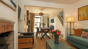 A living room with a fireplace, a dining area, and a staircase. - Chapelhay Cottage (Weymouth)