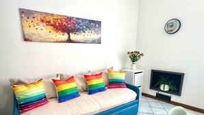 A room with a blue sofa bed, a television, a clock, and a painting on the wall. - Over the Rainbow in Sant Agnello (Sant'Agnello)