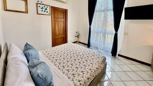 A bedroom with a bed, a wooden door, a window with curtains, and an air conditioning unit. - Over the Rainbow in Sant Agnello (Sant'Agnello)