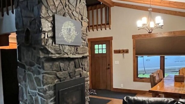 A stone fireplace, a black leather sofa, and a dining area with a wooden table and chairs.