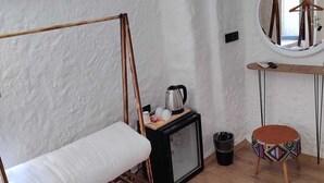A minimalist room with a wooden bed frame, a small TV, a round mirror, and a stool. - Baba Evi Alaçatı (Cesme)