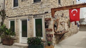 A stone building with the sign "BABA EVI" and a Turkish flag. There are potted plants outside and a wooden structure to the right. - Baba Evi Alaçatı (Cesme)