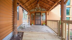 A wooden cabin with a porch, a rocking chair, and a stone wall. - Peaceful Getaway on Mio Pond (Mio)
