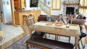 A spacious living area with a wooden dining table, leather sofa, and a stone fireplace. - Peaceful Getaway on Mio Pond (Mio)