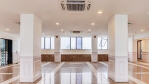 Un vestíbulo amplio con techos altos, ventanas grandes y un piso de mármol pulido.