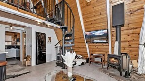 Un interior moderno con estilo de cabaña de madera, una chimenea, un comedor y una escalera.
