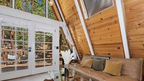 Un loft moderno con un vidrio que da a un patio exterior, una mesa de centro de cristal y un sofá de cuero.