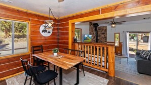 Un interior de madera con una mesa de comedor, sillas, un ventilador de techo y una chimenea de piedra.