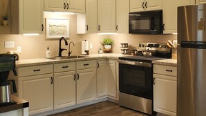 Een moderne keuken met witte kasten, roestvrijstalen apparatuur en een houten vloer.