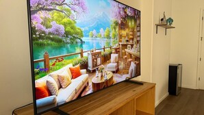 Un téléviseur à écran plat fixé sur un support en bois, diffusant un paysage pittoresque avec un lac, des arbres et un bâtiment comprenant un bar.