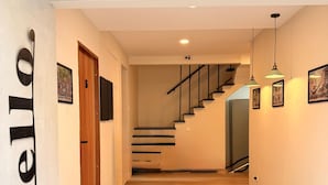 A modern interior with a wooden staircase, a minimalist design, and a 'hello' sign on the wall. - TwinTrees Kelawai (George Town)