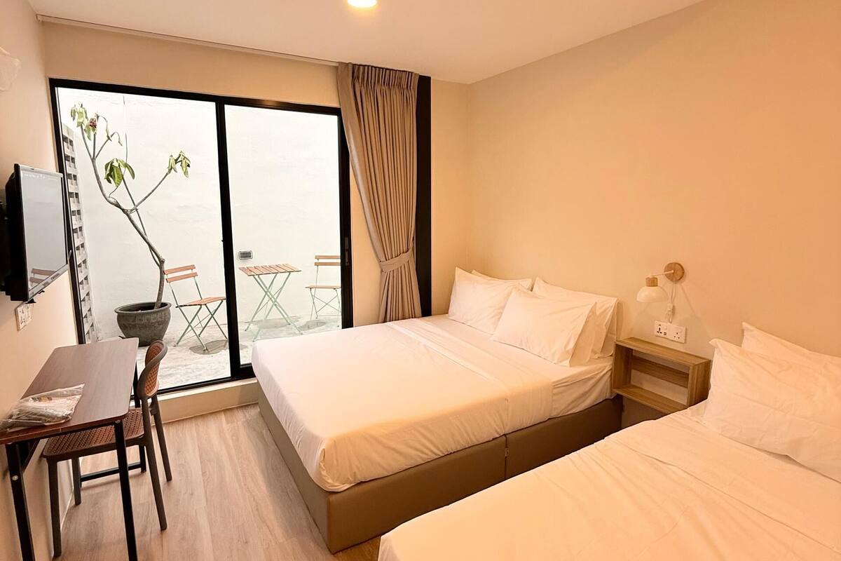 A hotel room with two beds, a desk, and a chair.