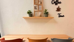 A wooden table with three chairs, a wall-mounted shelf with plants, and a 'Coffee Time' sign. - TwinTrees Kelawai (George Town)
