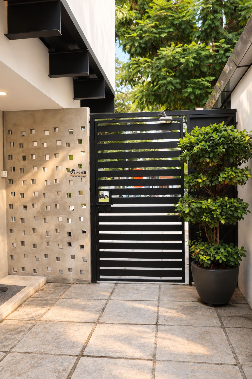 A gated entrance with a modern design, a potted plant, and a textured wall.