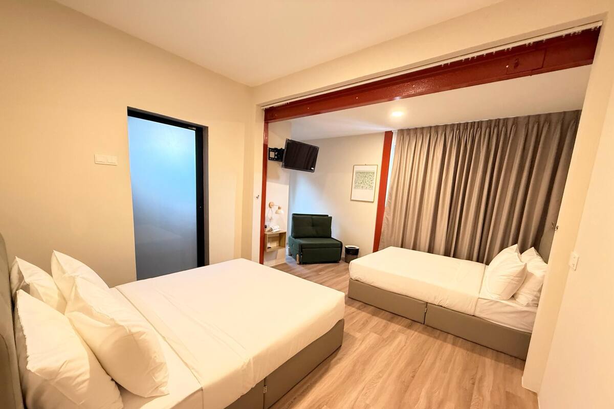 A hotel room with two beds, a TV, a desk, and a chair.