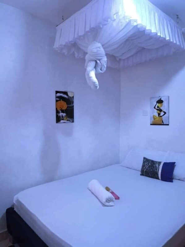 Ein Schlafzimmer mit einem Bett, einem Kopfkissen, einem zusammengerollten Handtuch und zwei Wandbildern.