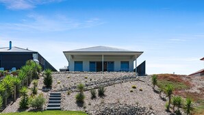 A modern house with a flat roof, a stone pathway leading to the entrance, and a clear blue sky. - 29 Blanche Pd, Hindmarsh Island (Hindmarsh Island)
