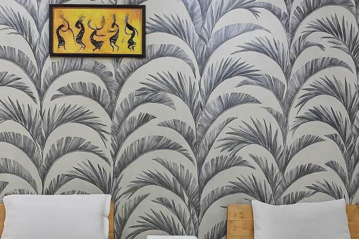 A room with two wooden beds, a small wooden nightstand, and a wall with a leaf-patterned wallpaper.