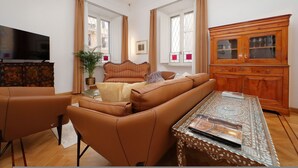 Een woonkamer met een bank, fauteuils, een salontafel en een houten kast.