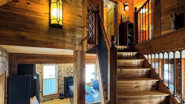 Een houten interieur met een trap, een open haard en uitzicht op het exterieur.