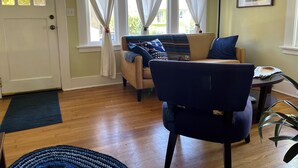 A living room with a sofa, a chair, a rug, and a window with curtains. - Charming 2-bedroom bungalow in Seward Park (Seattle)