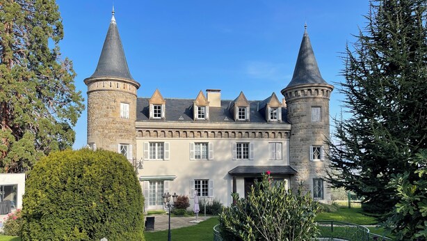 Un grande edificio in pietra con numerose torri e un giardino curato.