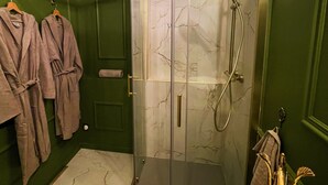Un bagno con doccia vetrata, vasca da bagno bianca e pareti verdi.