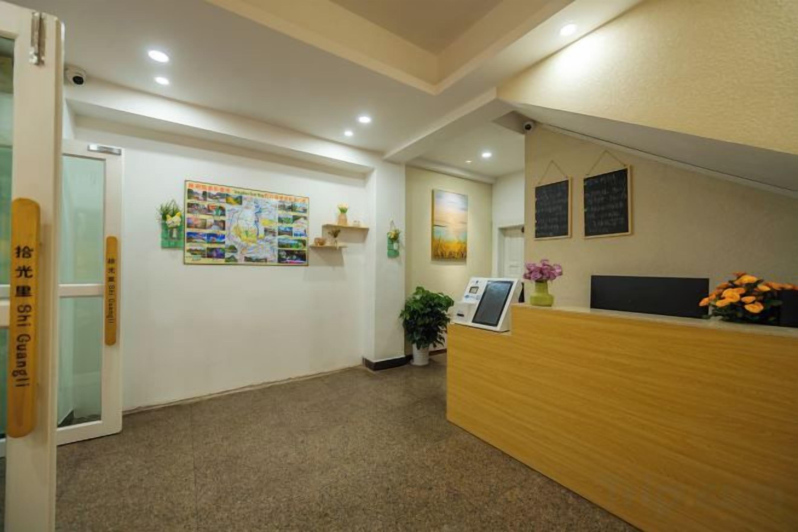A reception area with a wooden reception desk, a bulletin board, and a potted plant.