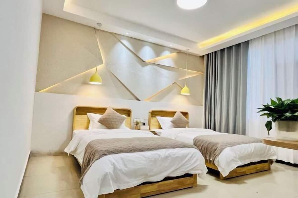 A modern hotel room with two beds, a geometric wall design, and a large window with curtains.