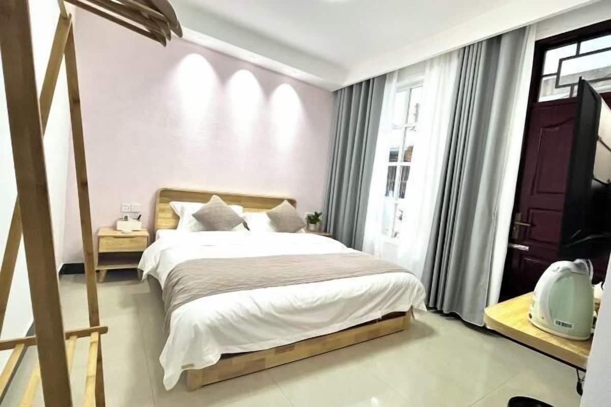 A bedroom with a bed, bedside table, and a kettle on a small table.
