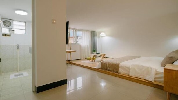 Ein Hotelzimmer mit Bett, Nachttisch, einem kleinen Tisch mit Stühlen, einem Fenster und einer Tür zu einem Badezimmer.