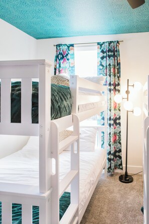 A bunk bed room with a ceiling fan, a floor lamp, and a window with curtains. - Spacious Lux Cincinnati Group Retreat: Sauna/Spa, Fire pit, 5 min DT (Cincinnati)