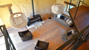 A cozy living room with a fireplace, two sofas, a dog rug, and a large woven floor lamp.