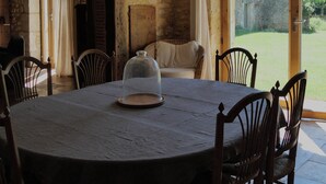 A rustic dining area with a round table, wooden chairs, and a glass dome centerpiece.