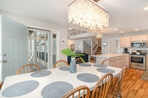 A dining area with a white table, blue placemats, and wooden chairs. - Don't Worry Beach Happy | Your Beach Getaway! (Ocean Isle Beach)