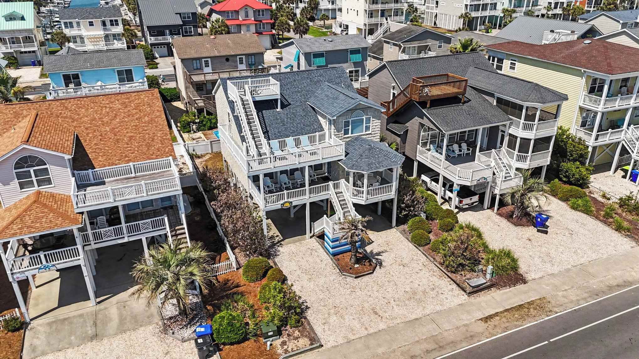 A coastal residential area with multiple two-story houses featuring balconies and a sandy beach in the foreground.