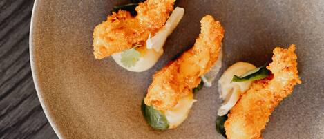 A plate with three pieces of breaded food, possibly shrimp, on a textured ceramic plate.