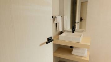 A bathroom with a white sink, a mirror, and a towel rack.
