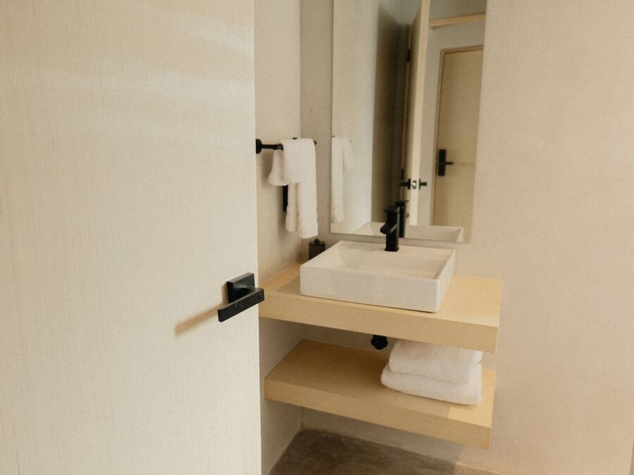 A bathroom with a white sink, a mirror, and a towel rack.
