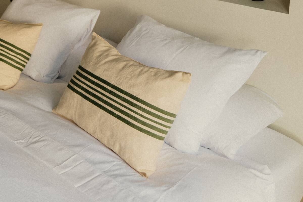 Ein ordentlich eingerichtetes Schlafzimmer mit Bett, Kissen und Regalen mit Dekoration.