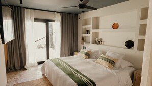 Ein Schlafzimmer mit einem großen Bett, einem Deckenventilator und Blick ins Freie.