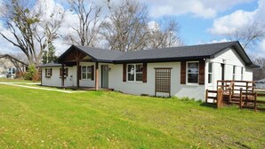 Ein eingeschossiges Haus mit Veranda, Garage und umzäunter Garten.
