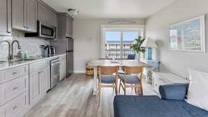 Eine kompakte Küche mit modernen Geräten, ein Essbereich mit einem Holztisch und Stühlen sowie ein Ausblick durch ein großes Fenster.