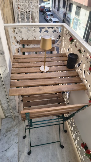 Un banco de madera con una lámpara en un balcón con barandilla decorativa.