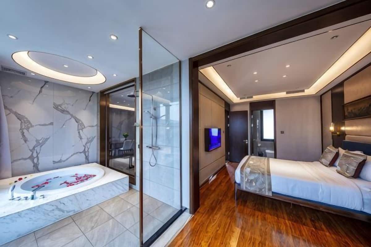 Een moderne slaapkamer met een groot bed, een douchecabine van glas en een betegelde badkamer met marmer.
