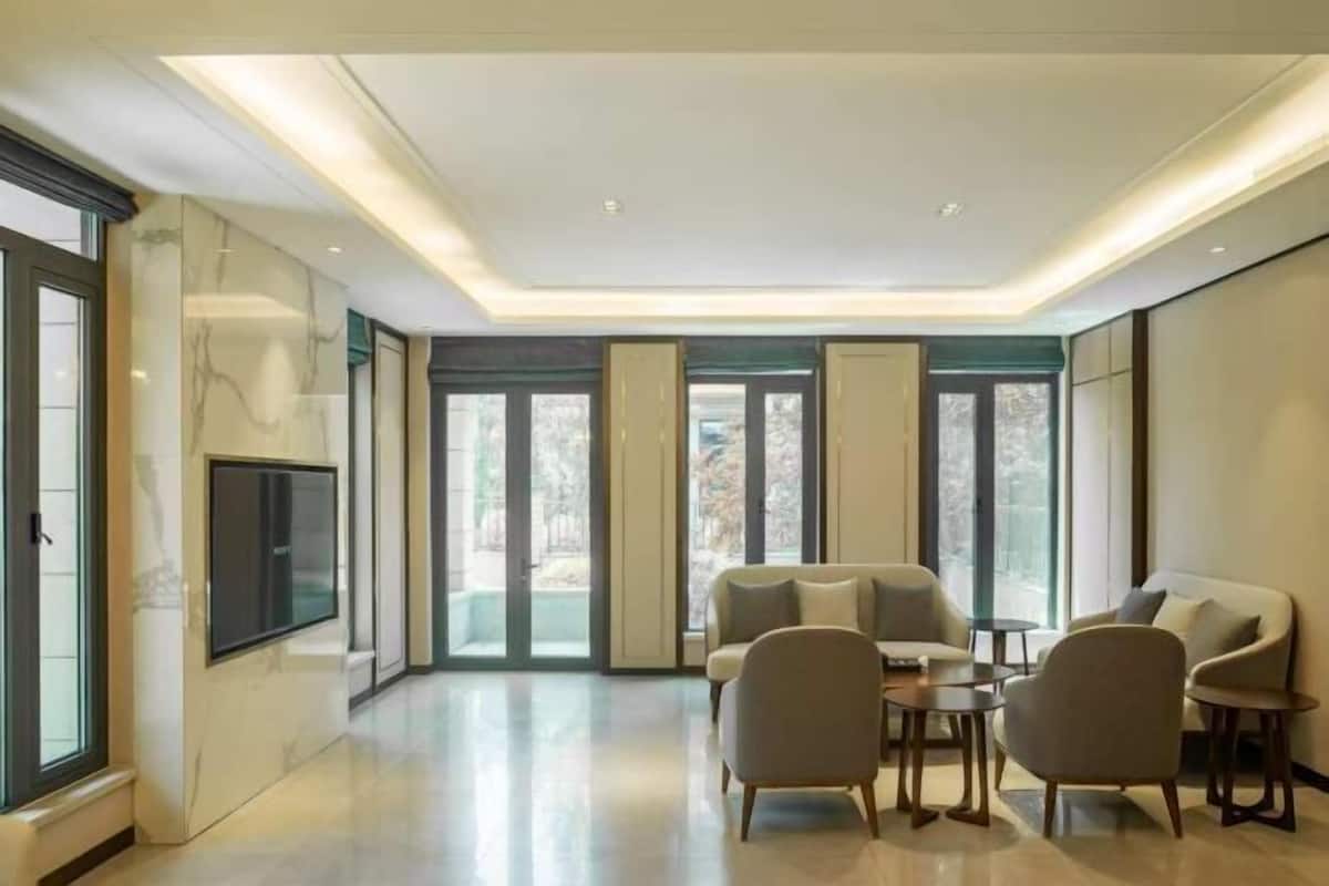 Een moderne woonkamer met een flatscreen televisie, comfortabele zitplaatsen en grote ramen.