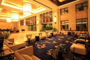 A spacious lobby with a carpeted floor, seating areas, and large windows.