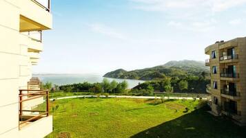 A building with a balcony overlooking a grassy area and a body of water.