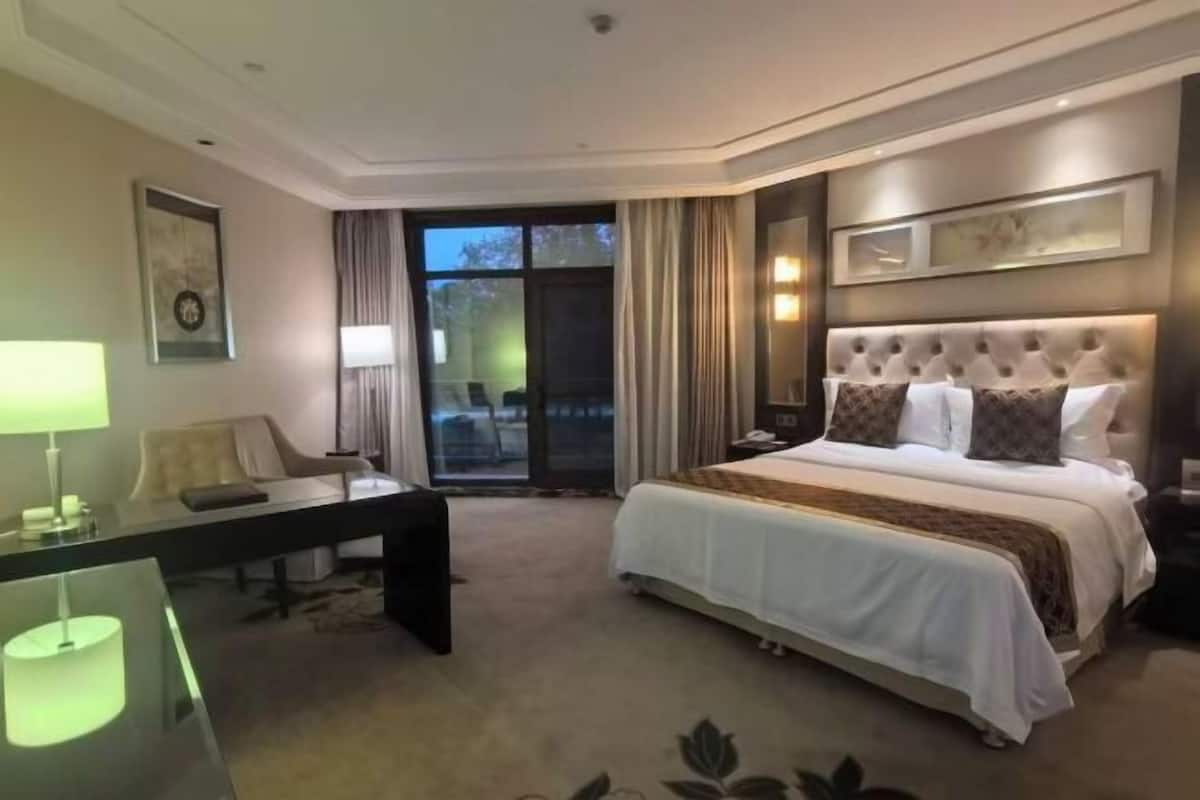 Een hotelkamer met een groot bed, een bureau, een stoel en uitzicht op de omgeving.